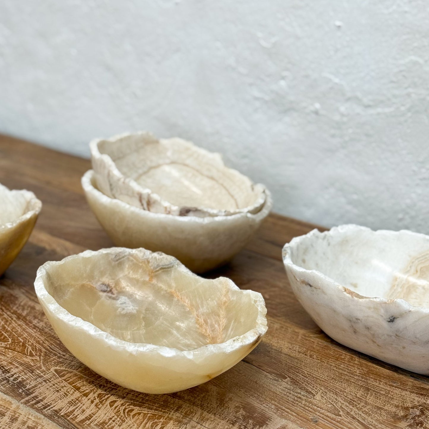 Set of raw stone bowls on a wooden surface with a light gray background