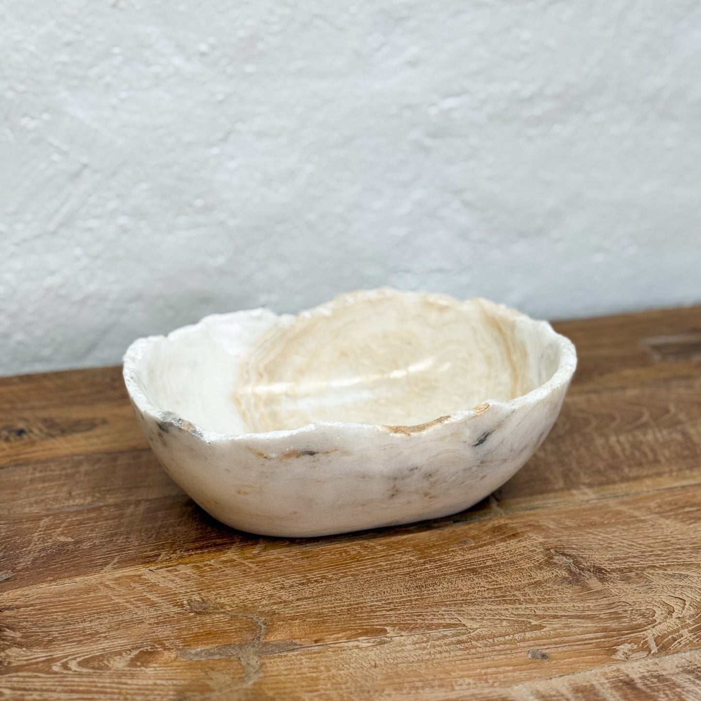 Marble bowl on a wooden surface with a textured white wall background