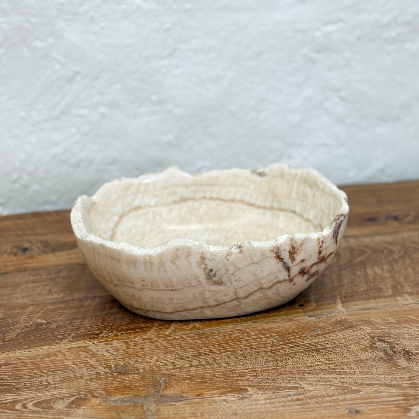 Ceramic bowl on a wooden surface with a textured white wall background
