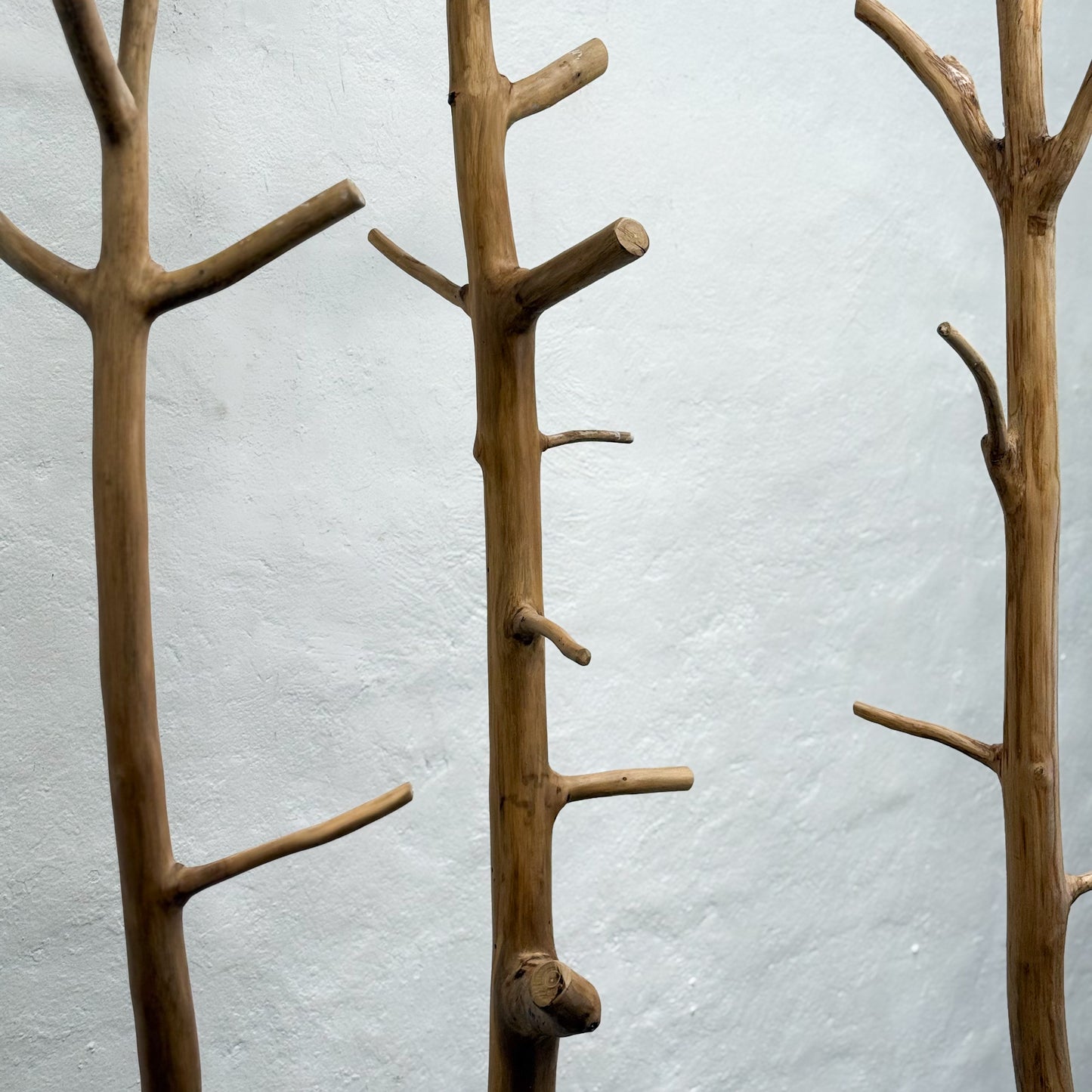 Three wooden branch wall hooks against a light gray background