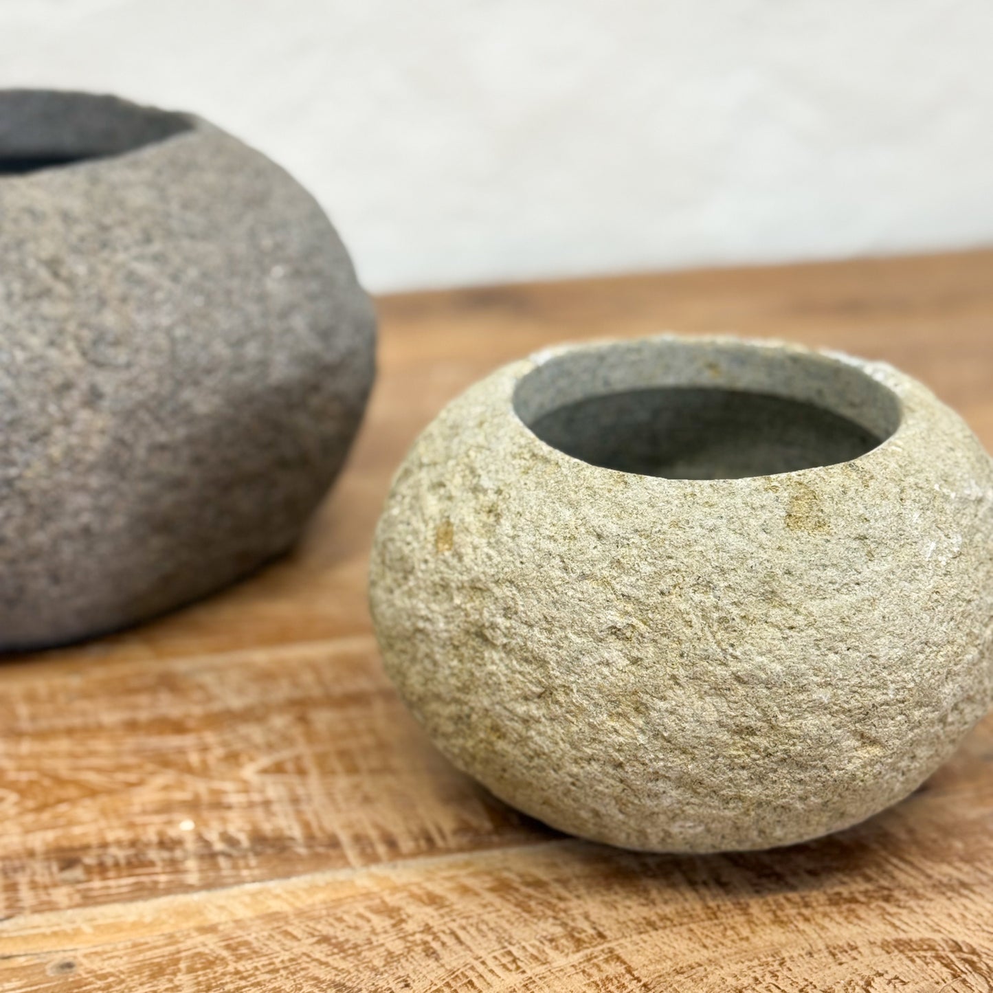 Two stone bowls on a wooden surface with a white background