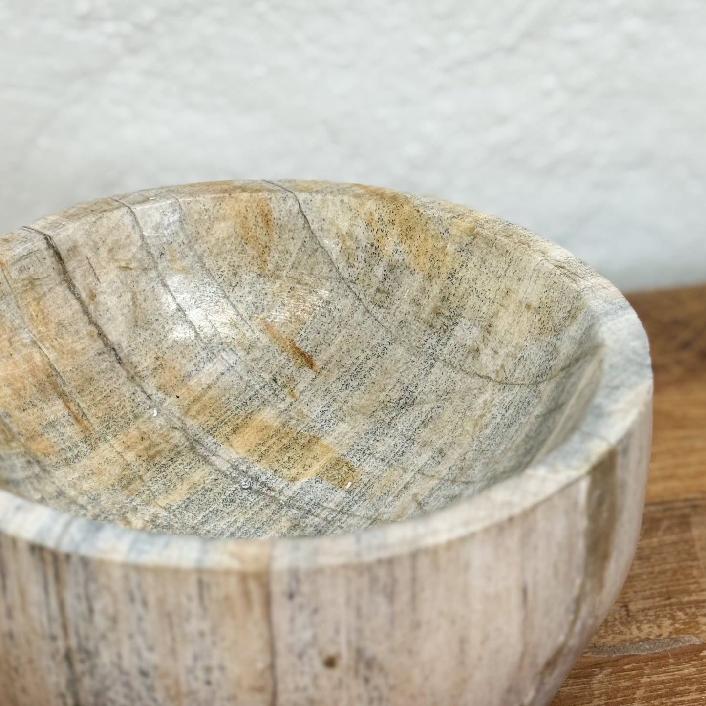Close-up of a stone bowl on a wooden surface with a neutral background