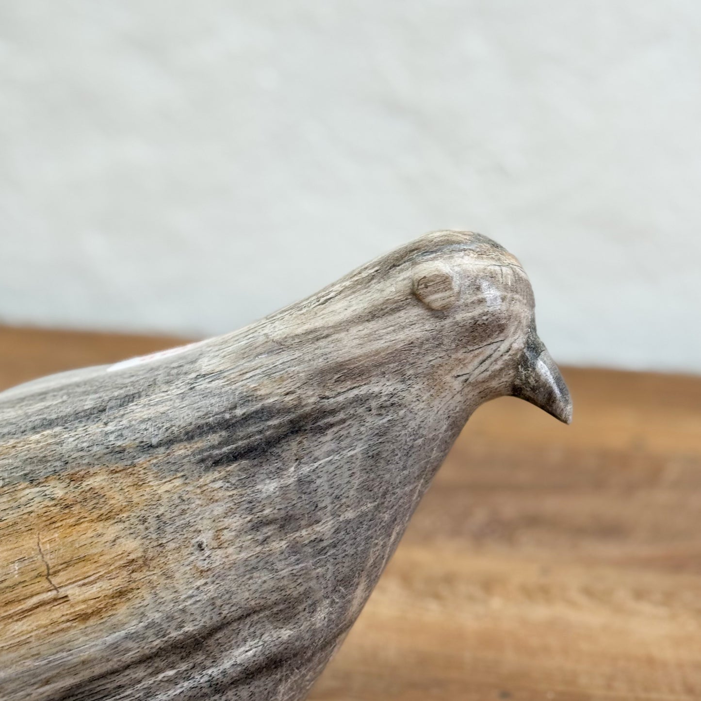Wooden bird sculpture on a wooden surface with a neutral background