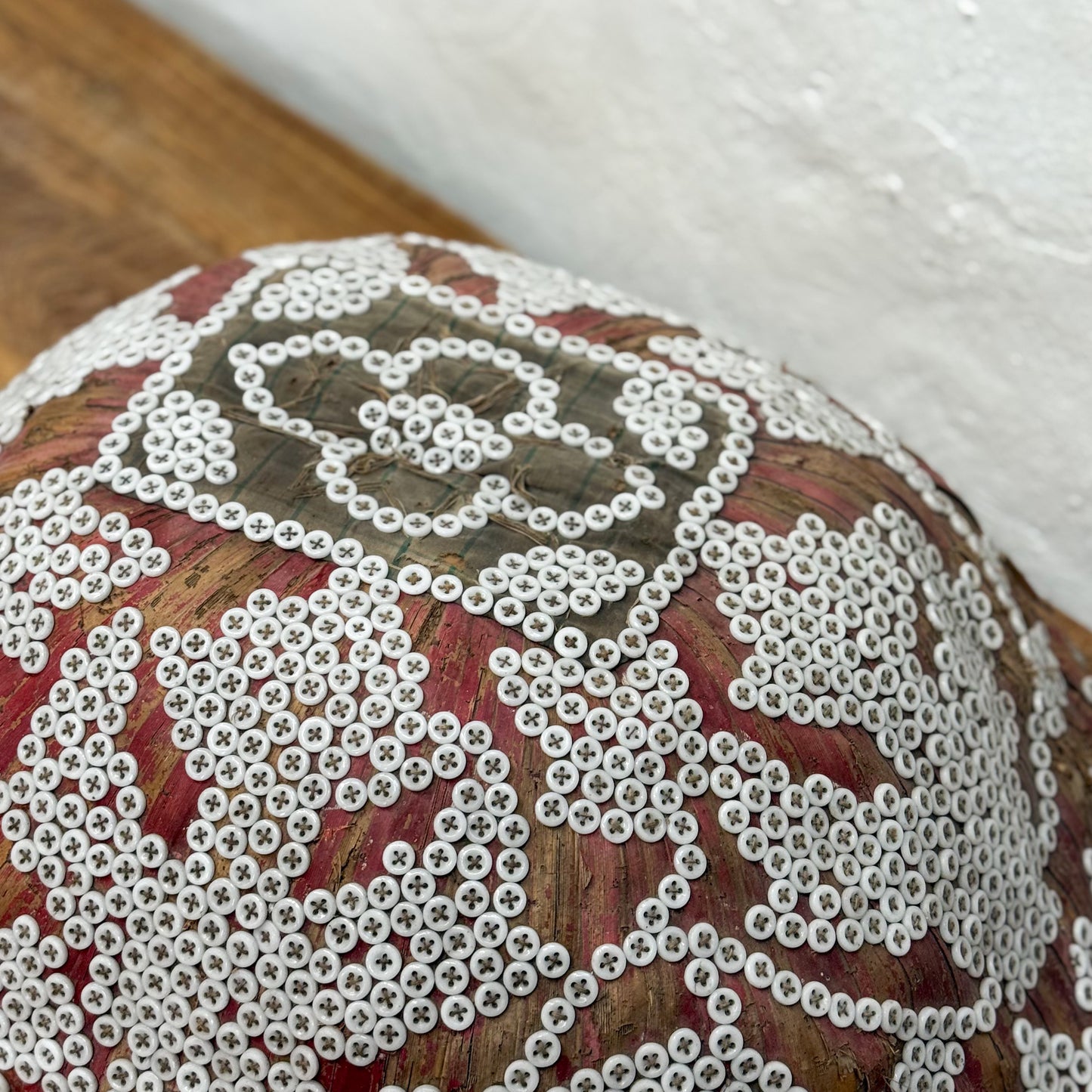 Close-up of a decorative item with white beadwork on a wooden surface.