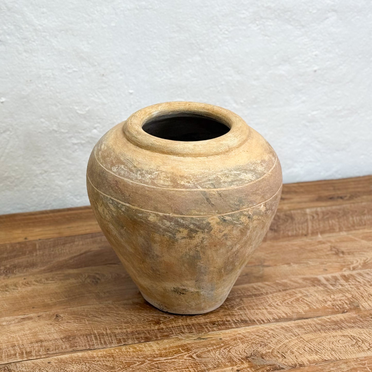 Decorative stone vase on a wooden surface with a light gray textured wall background