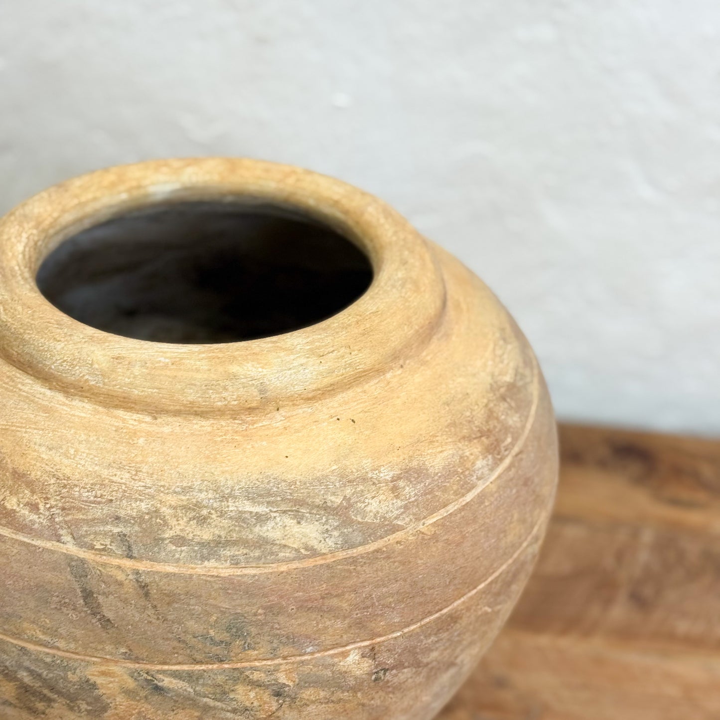 Close-up of a rustic wooden vase on a wooden surface with a white background