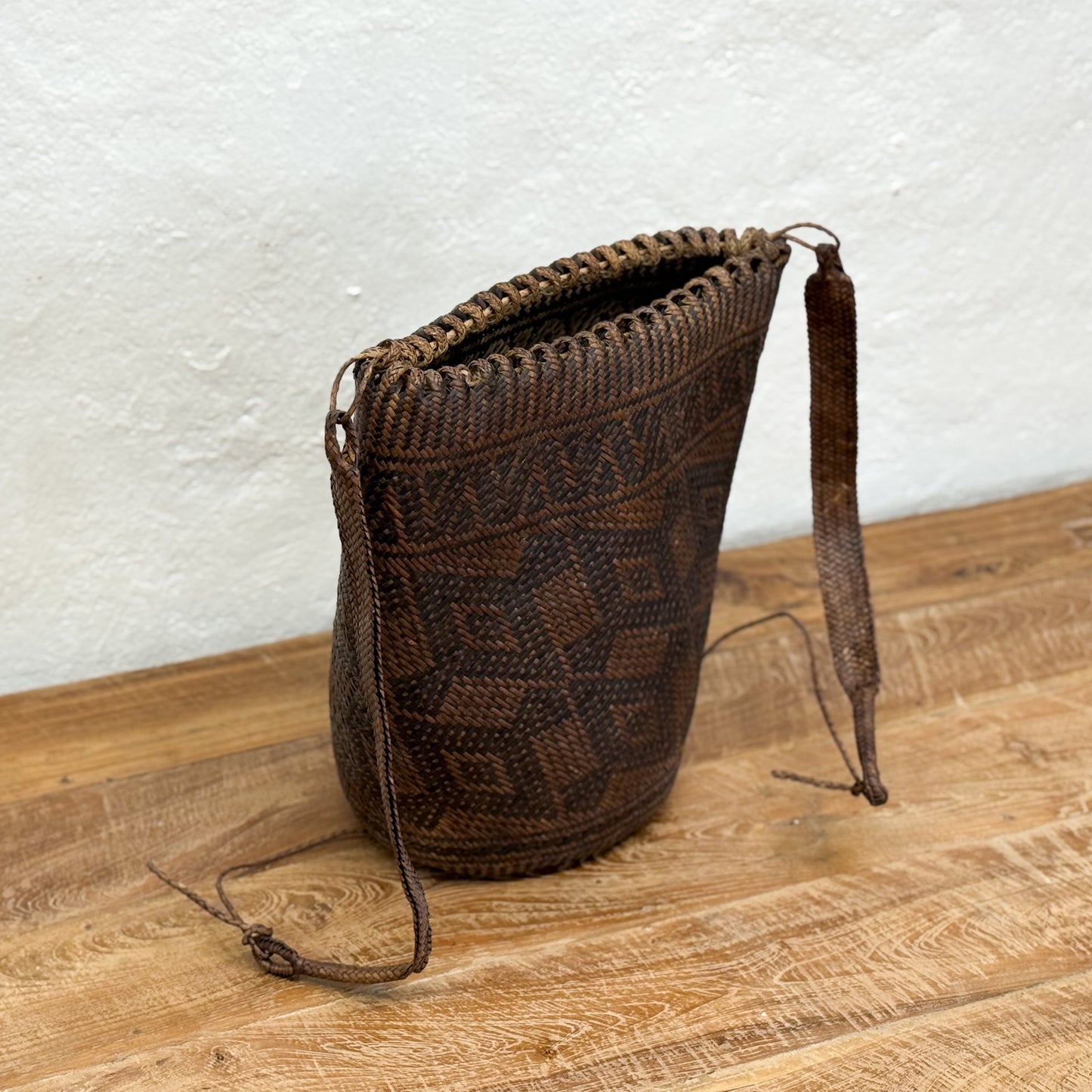 Brown woven bag with a strap on a wooden surface