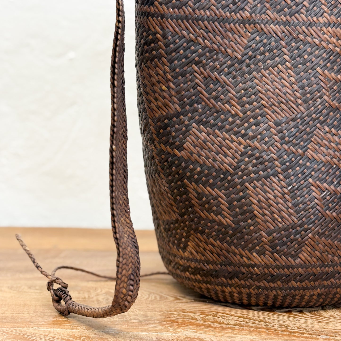 Woven brown bag with a patterned strap on a wooden surface