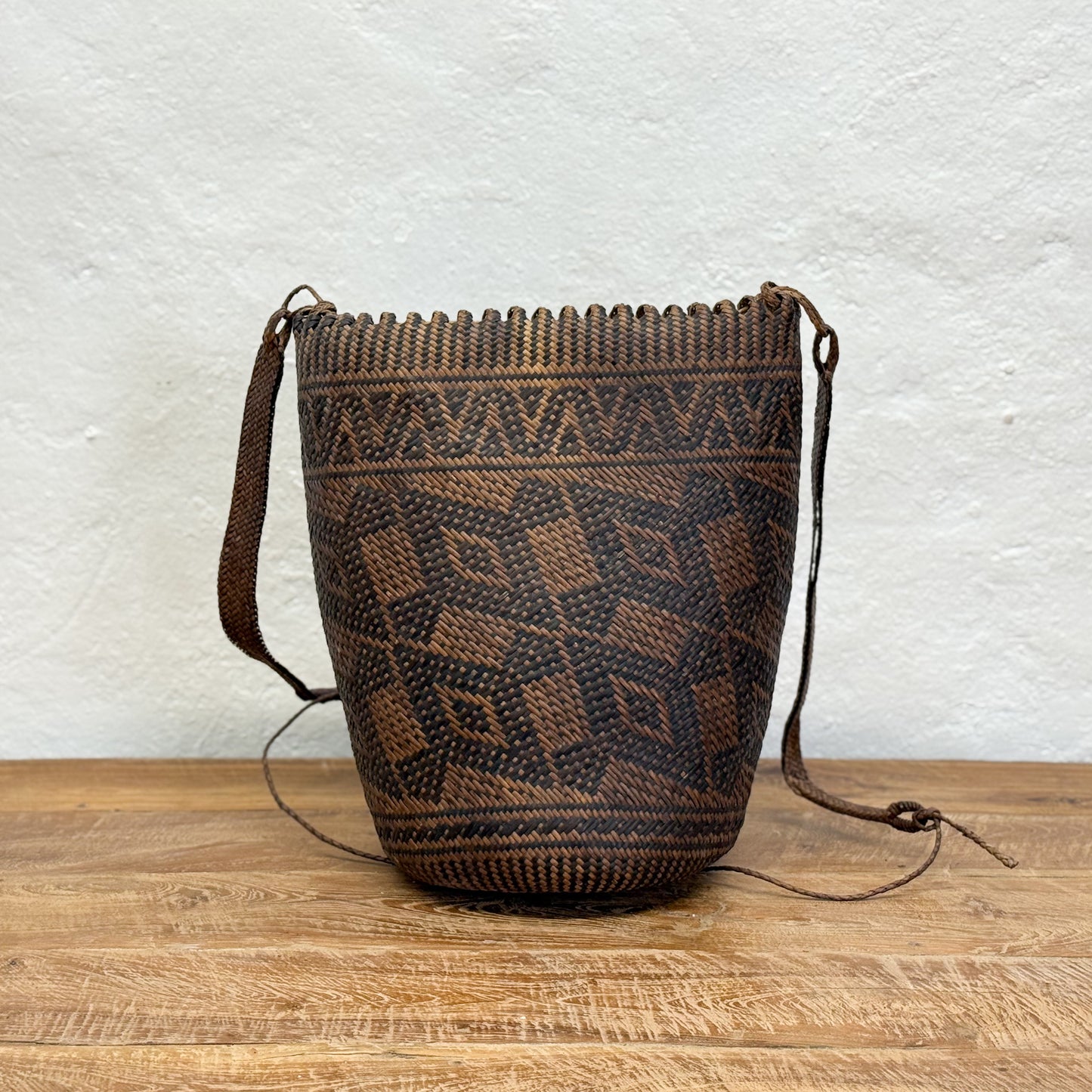 Woven bag with geometric pattern on a wooden surface and light gray background