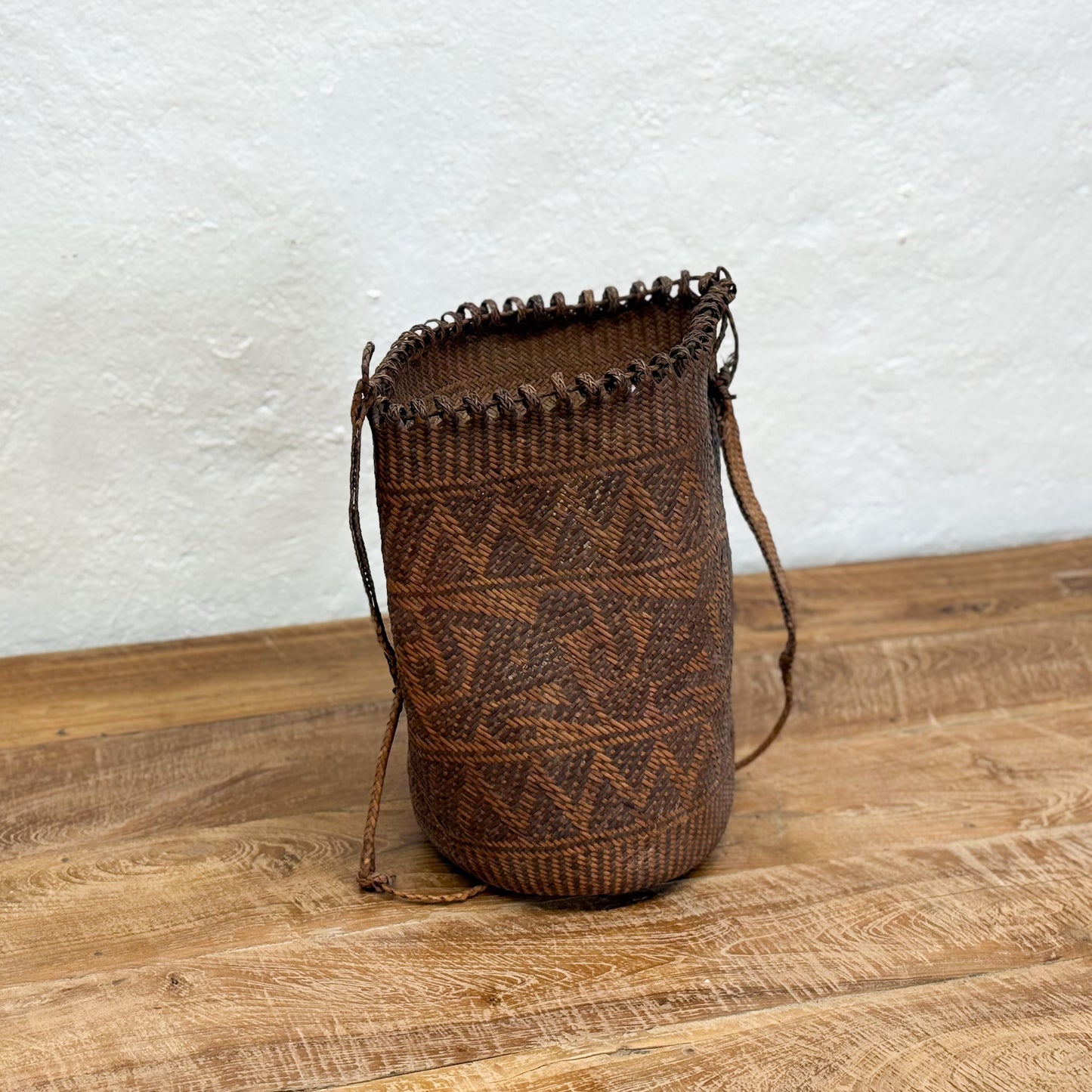 Woven brown basket with decorative patterns on a wooden surface