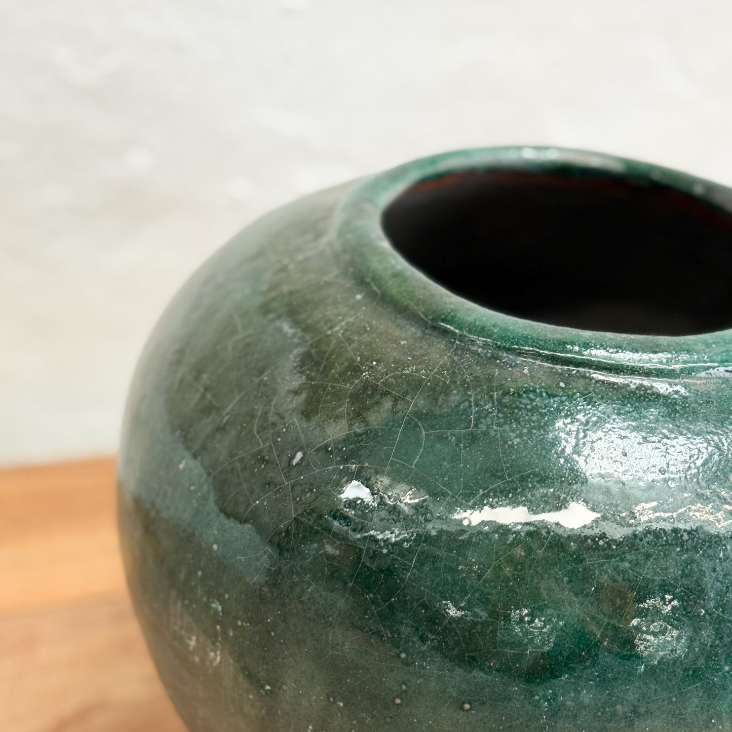 Green ceramic pot on a wooden surface with a white background