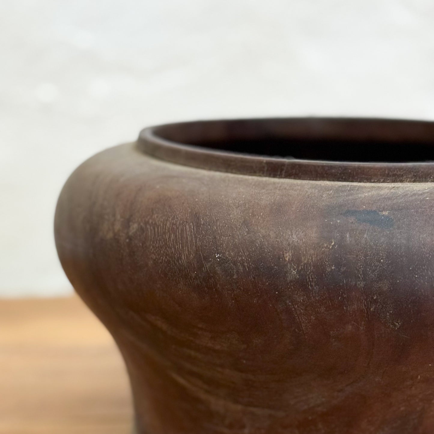 Close-up of a brown ceramic pot on a wooden surface with a blurred background