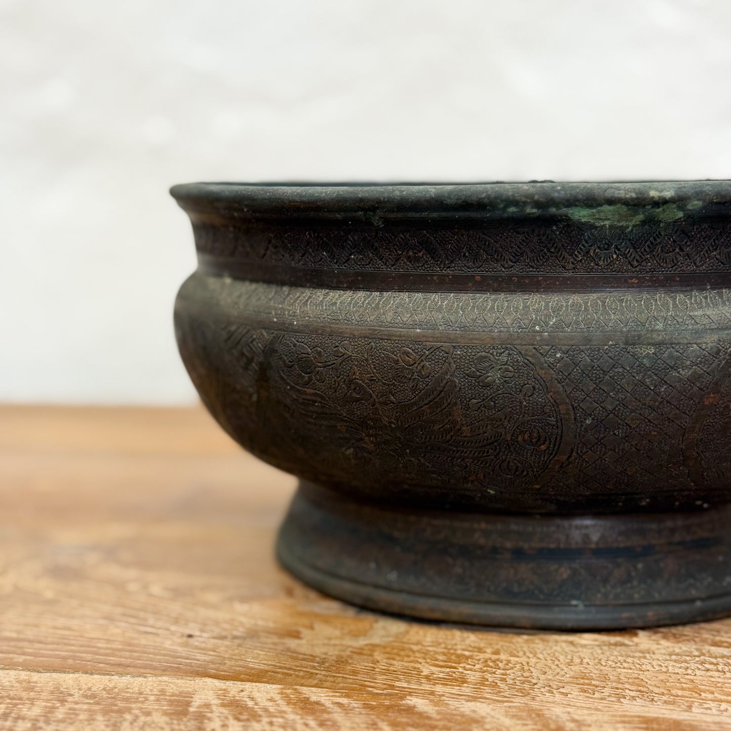 Bronze bowl with intricate patterns on a wooden surface