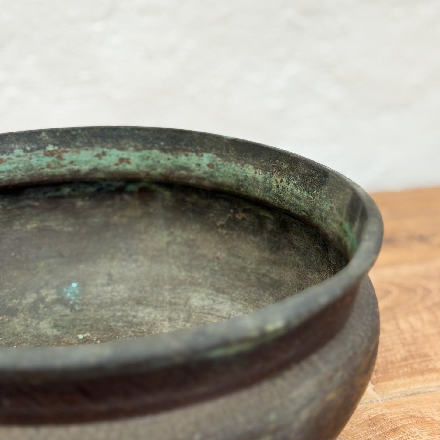 Bronze pot with green patina on a wooden surface