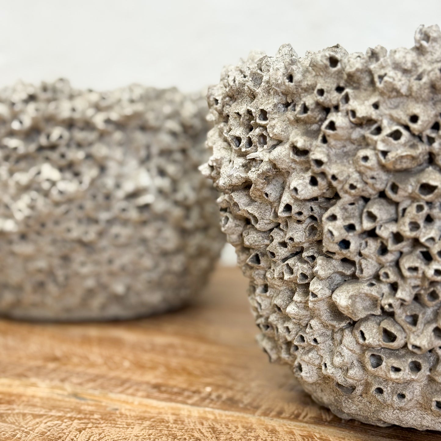 Two textured stone bowls on a wooden surface with a neutral background