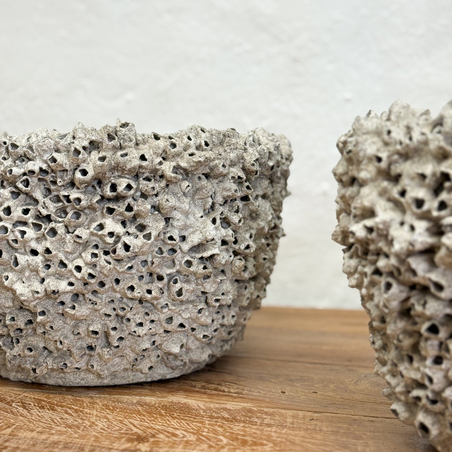 Two textured stone bowls on a wooden surface with a neutral background