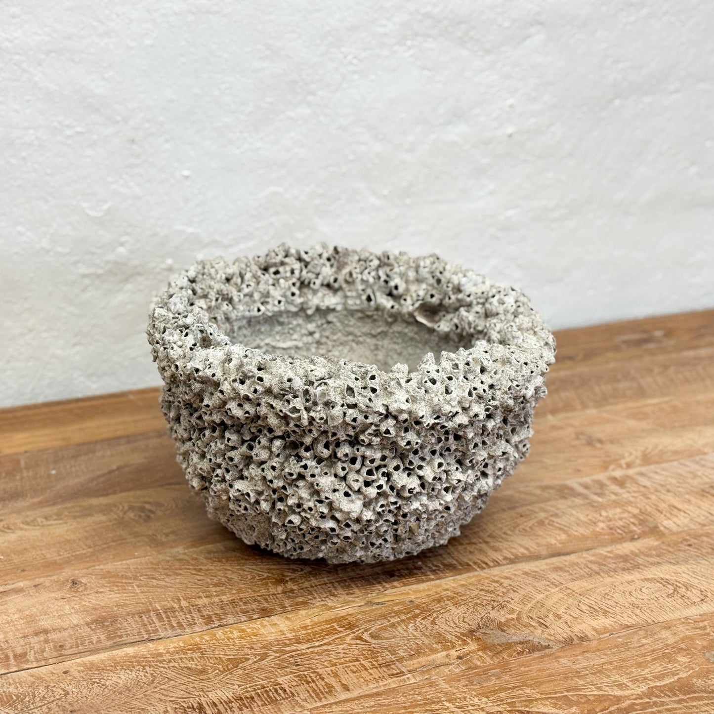 Textured ceramic bowl on a wooden surface with a light gray background