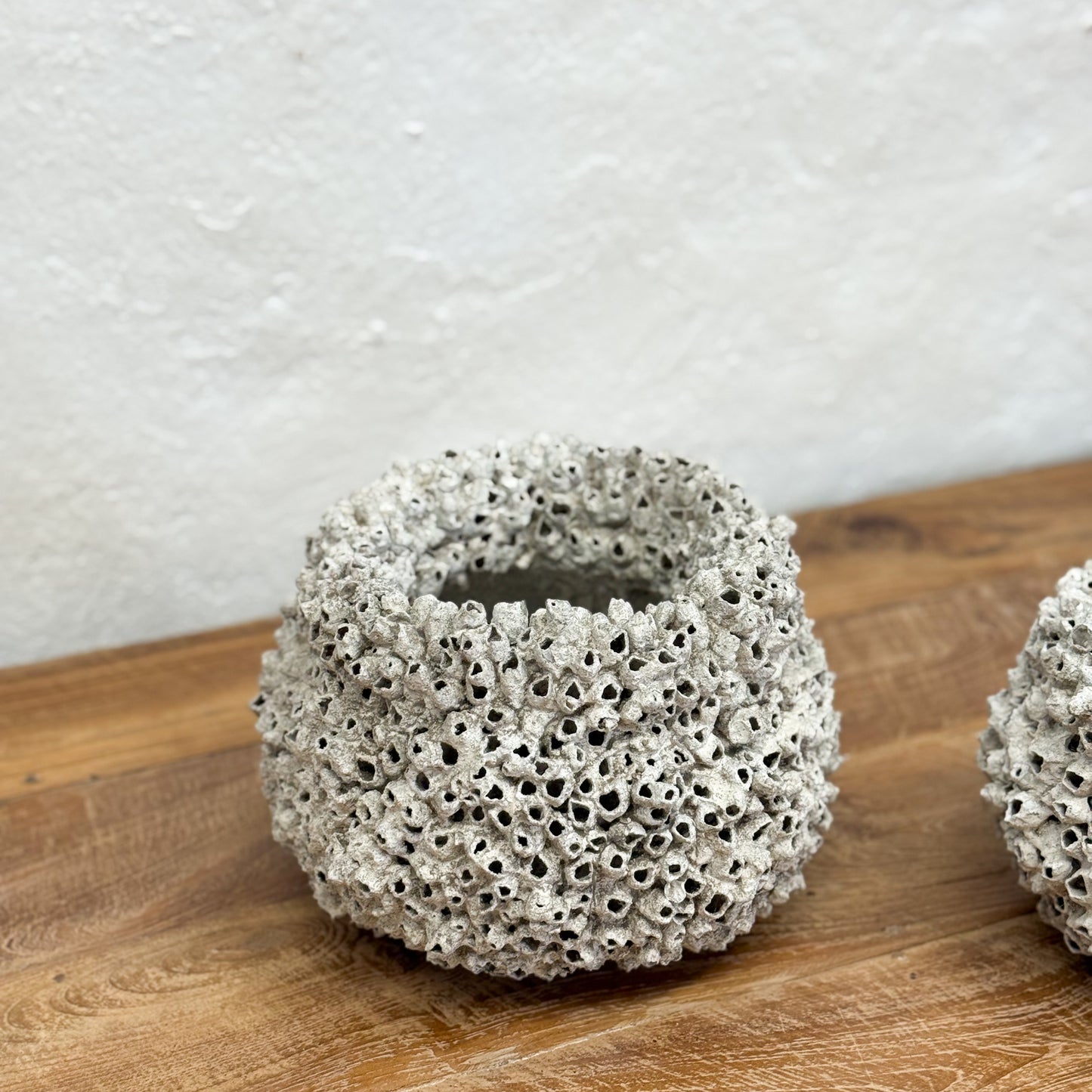 Textured ceramic pot on a wooden surface with a light gray background