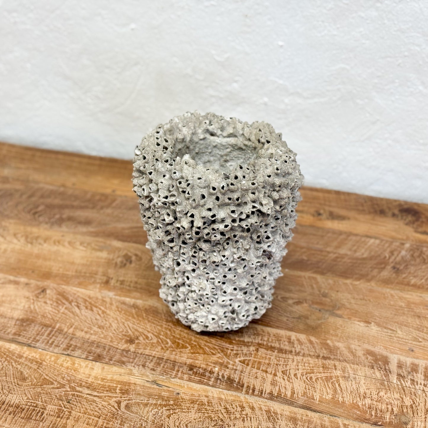 Textured stone sculpture on a wooden surface with a white background