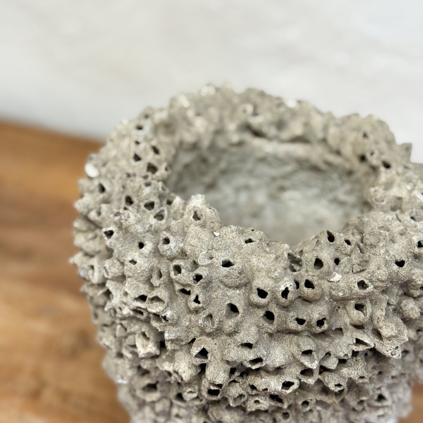 Textured gray ceramic vase on a wooden surface with a blurred background