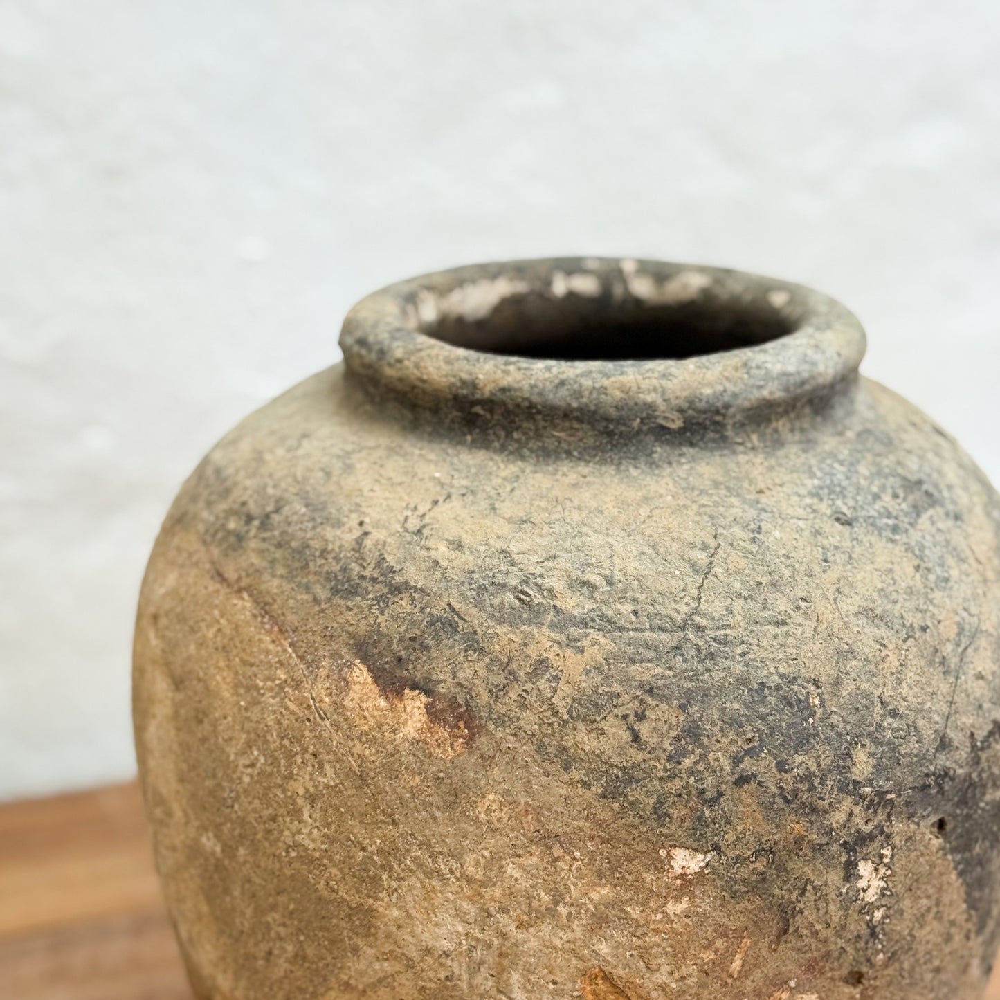 Vintage terracotta pot on a wooden surface with a light gray background