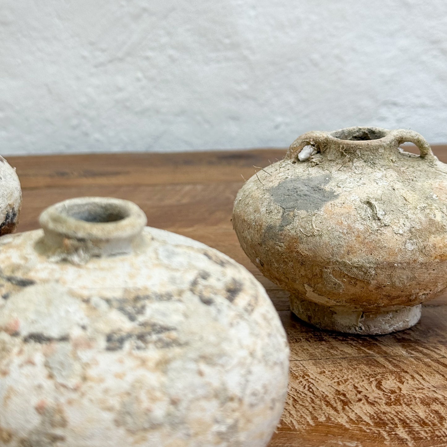Two rustic ceramic pots on a wooden surface with a neutral background