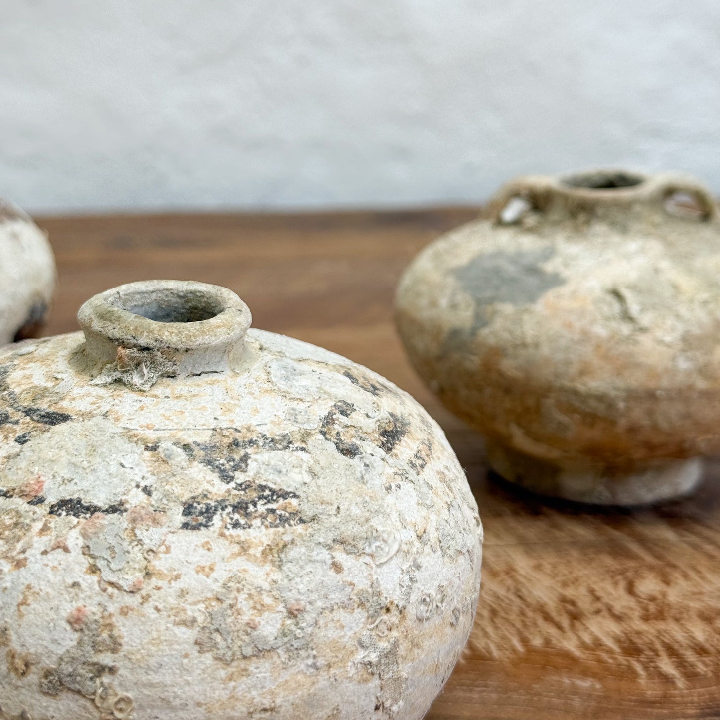 Two rustic ceramic pots on a wooden surface with a neutral background