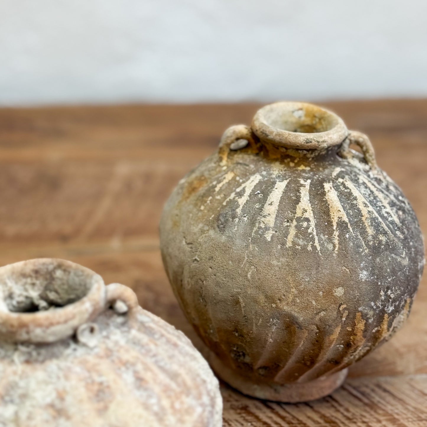 Two rustic clay pots on a wooden surface with a blurred background