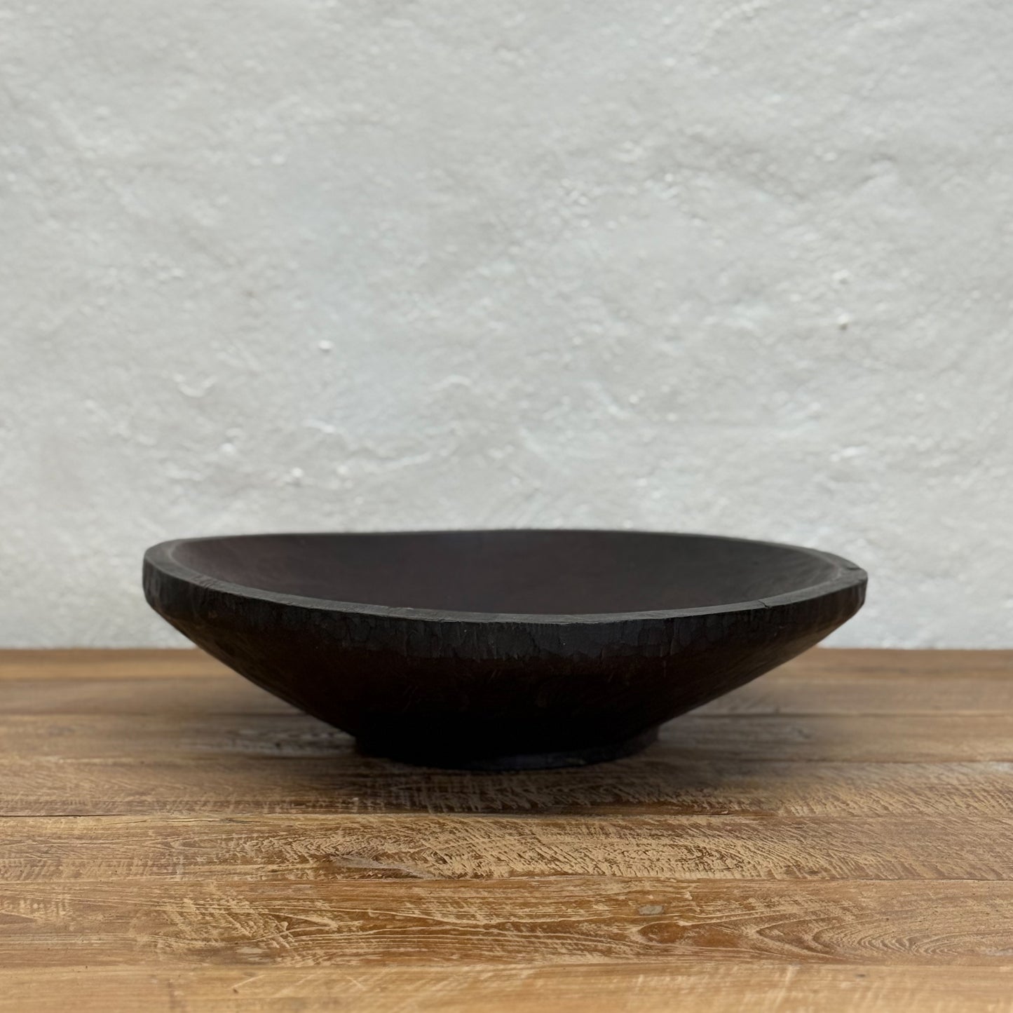 Black ceramic bowl on a wooden surface with a textured gray wall background