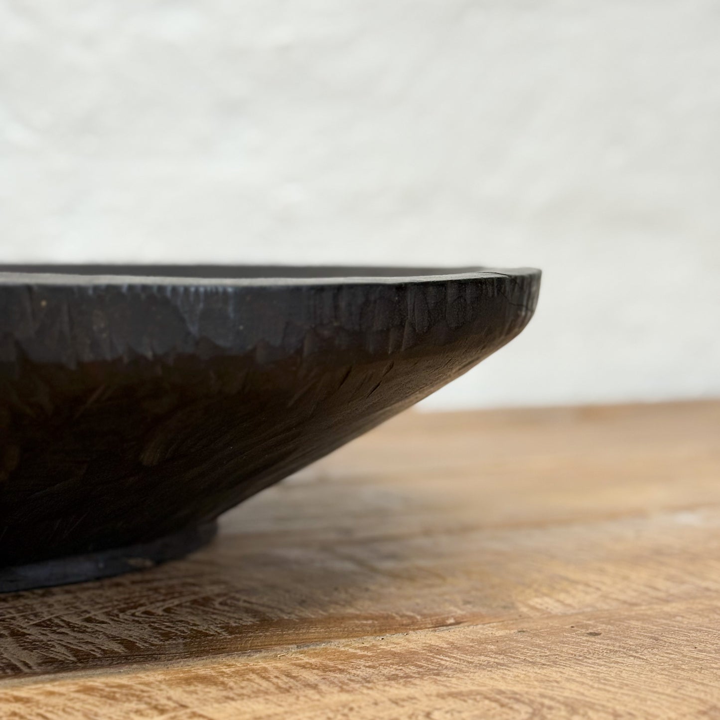 Black ceramic bowl on a wooden surface with a blurred background