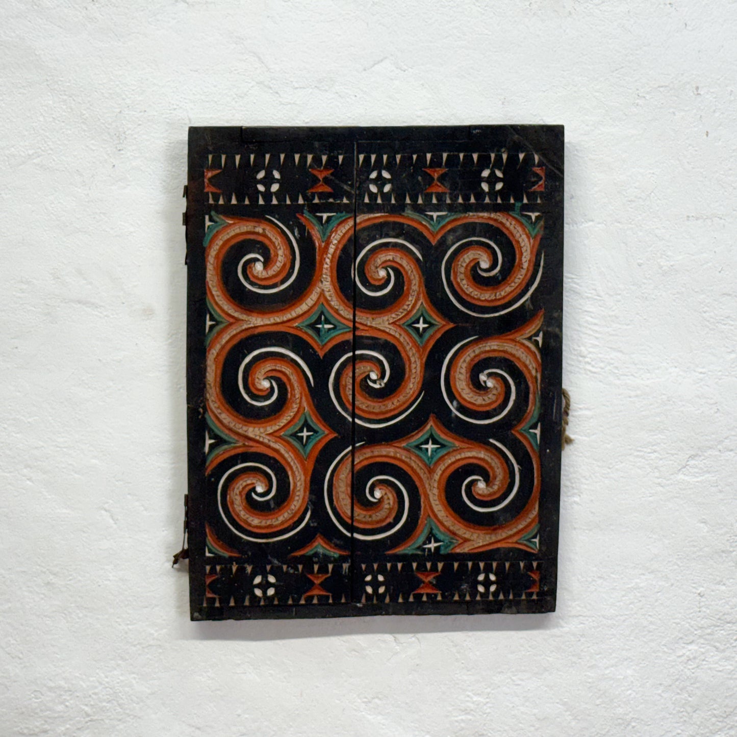 Decorative wooden panel with intricate spiral pattern on a white wall