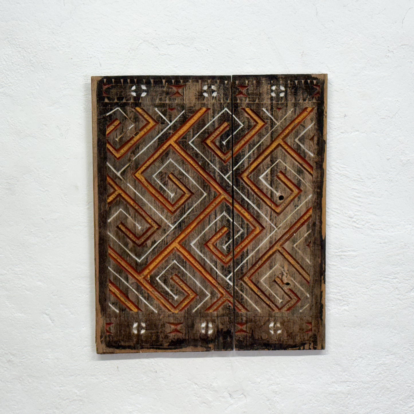 Decorative wooden panel with geometric pattern on a white wall