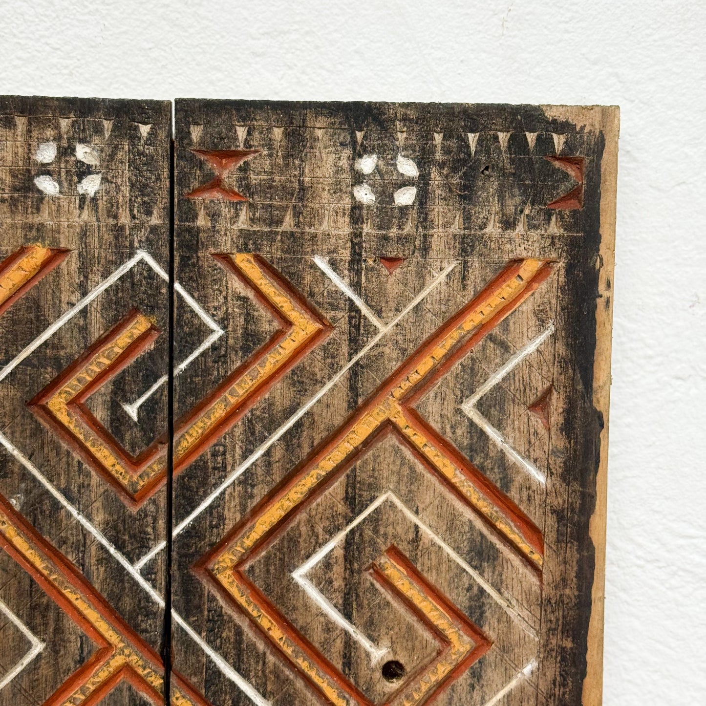 Wooden panel with geometric carvings on a white background