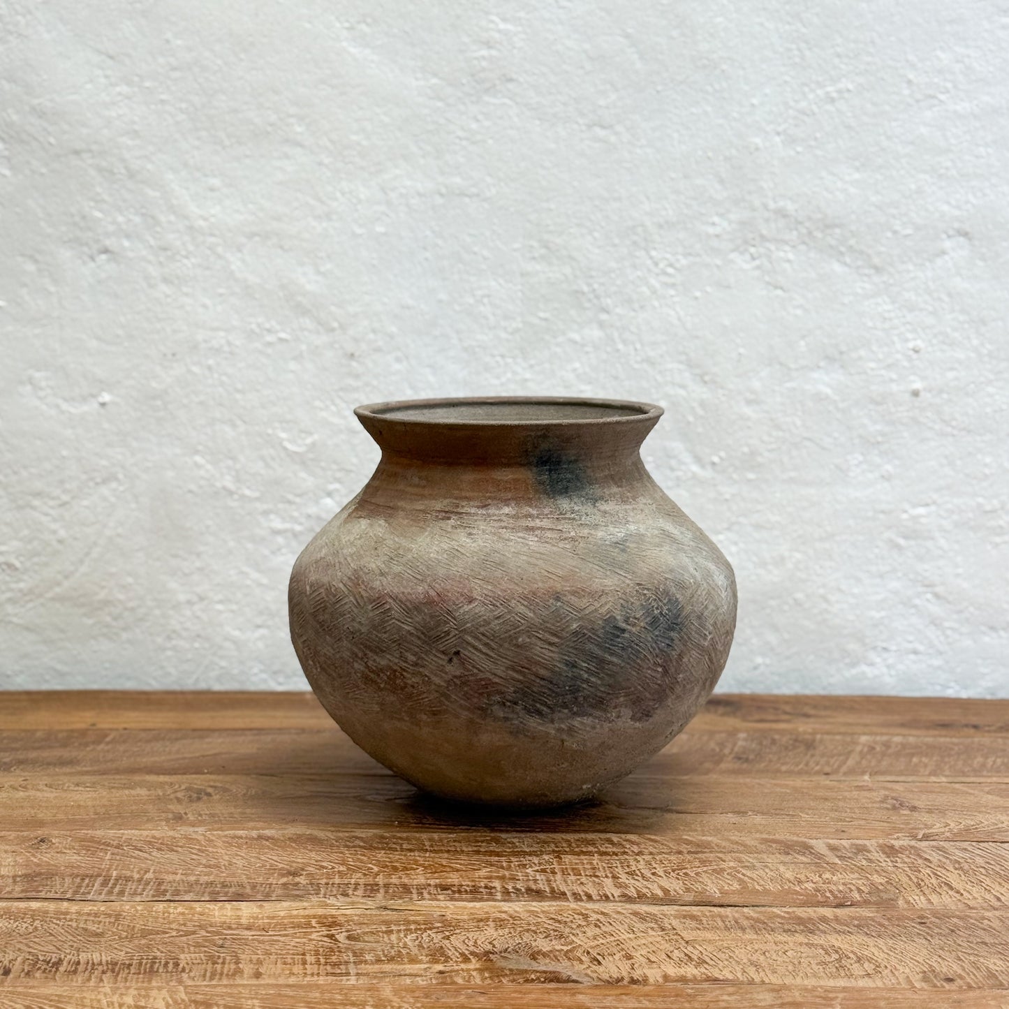 Brown ceramic pot on a wooden surface with a light gray textured background