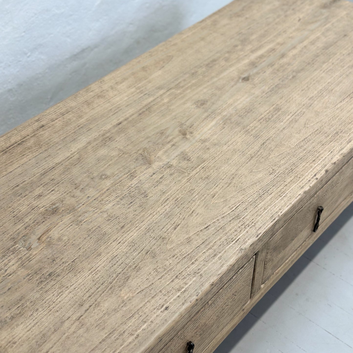 A rustic elm coffee table with three drawers, positioned against a plain background.