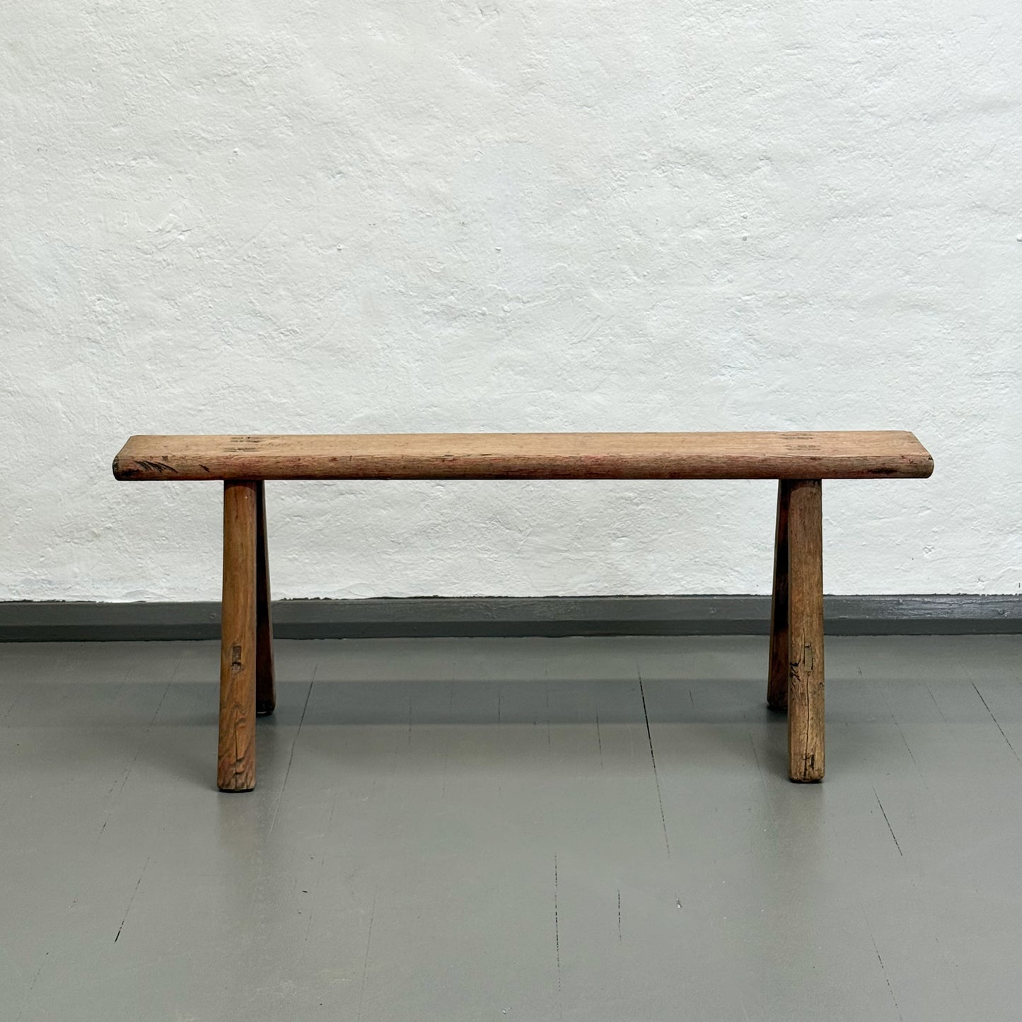 Wooden bench against a textured white wall
