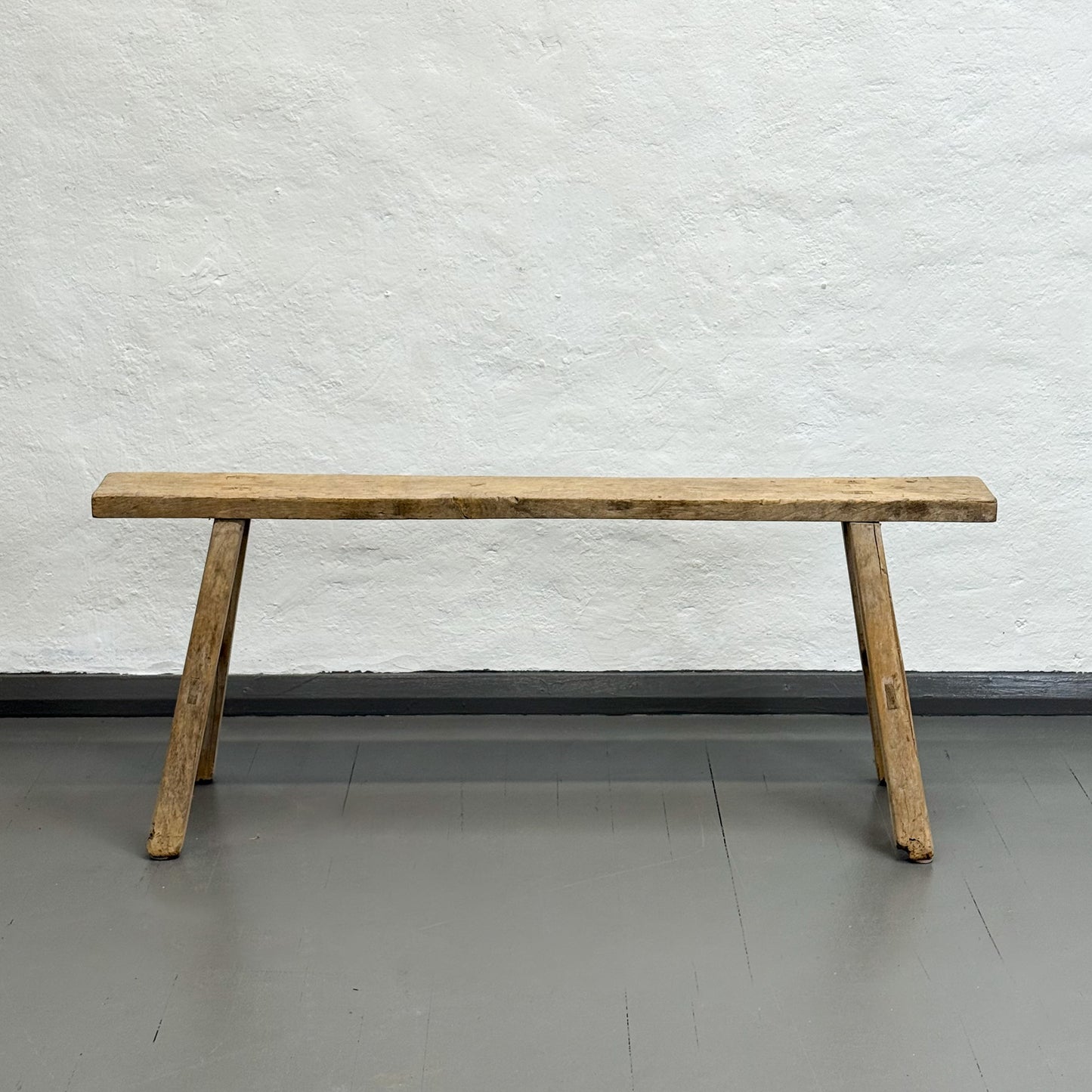 Wooden bench against a white textured wall