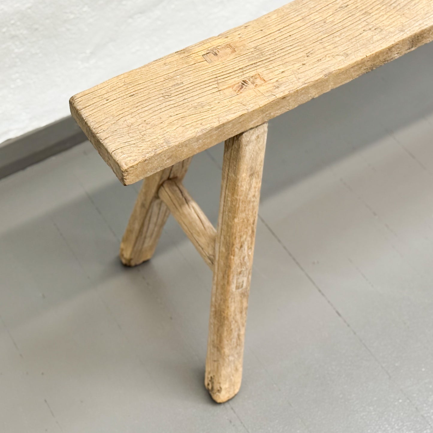 Wooden bench with a simple design on a light gray floor.