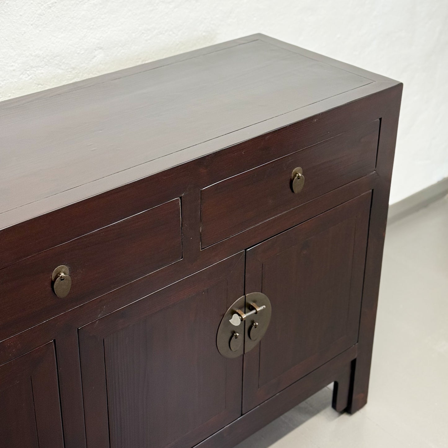 Dark wooden sideboard with brass handles on a white background