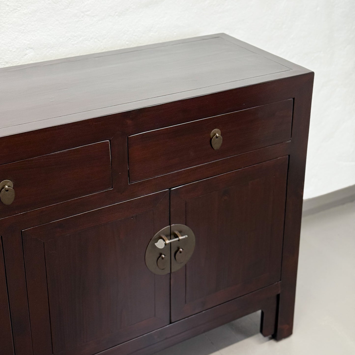 Dark wooden sideboard with brass handles on a white background