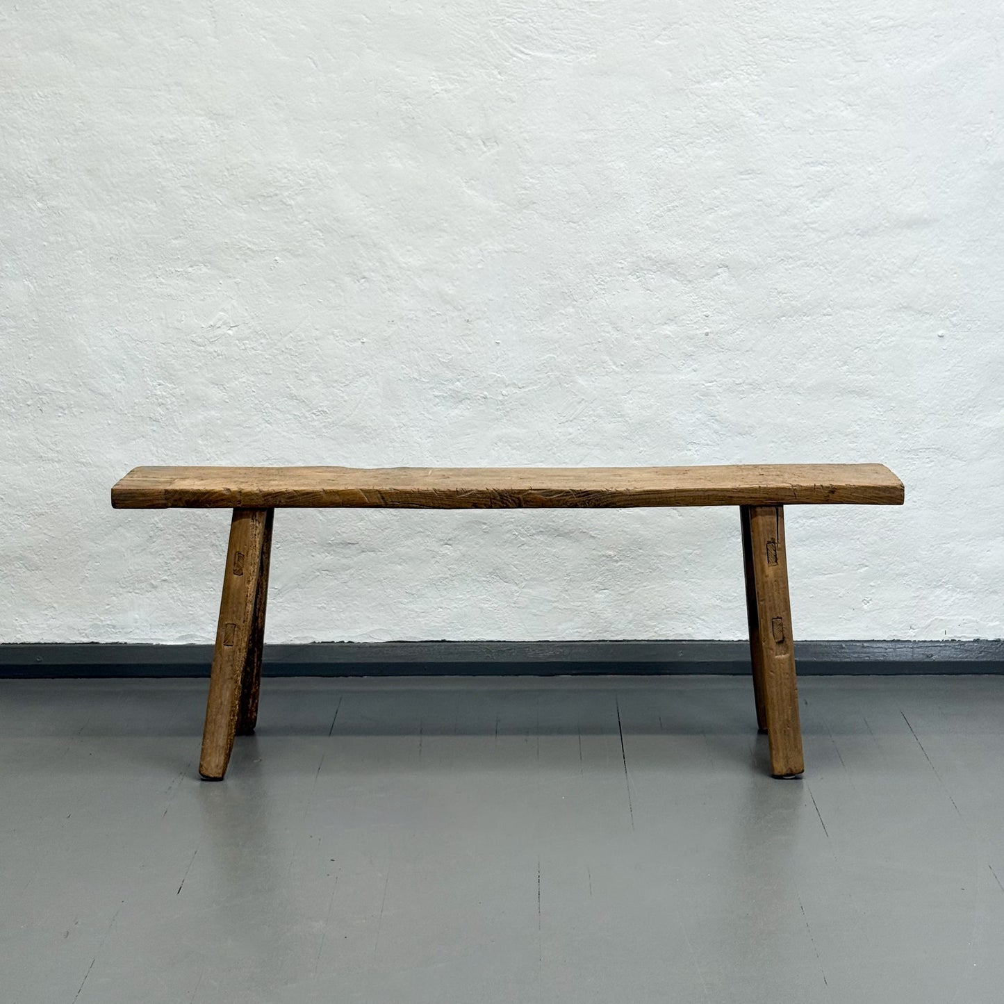 Wooden bench against a textured white wall