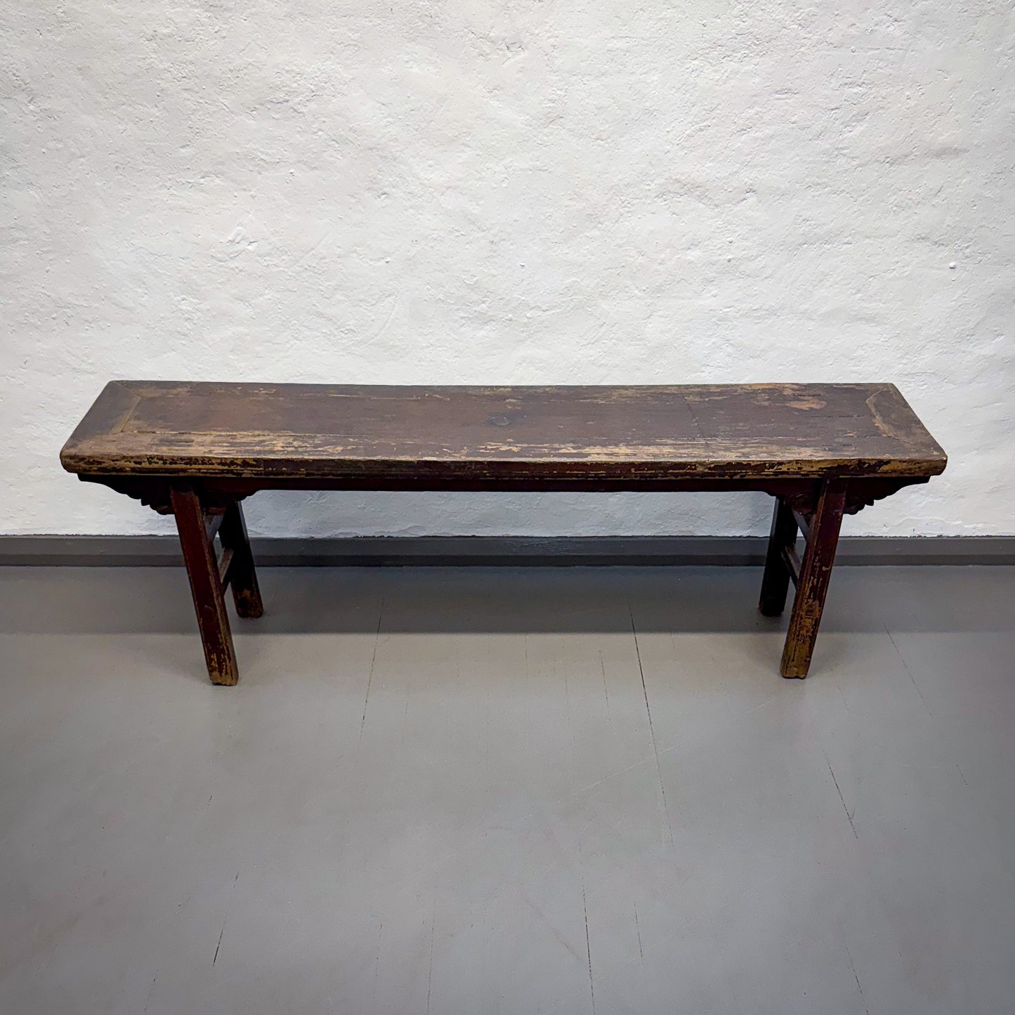 Wooden bench against a plain white wall