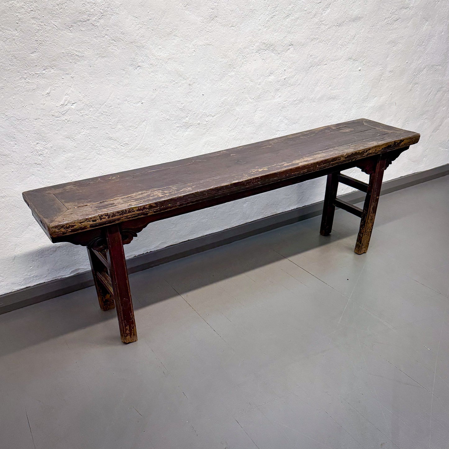 Old wooden bench against a textured white wall