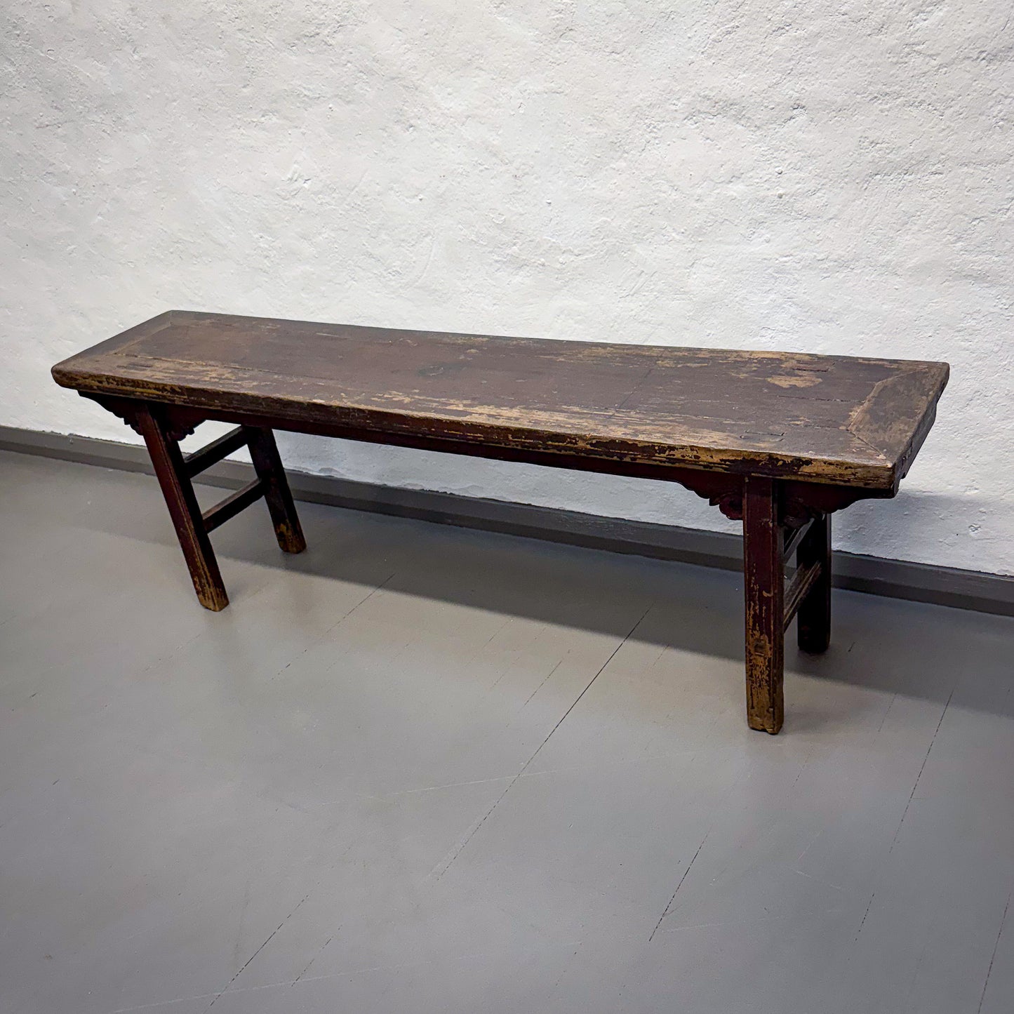 Old wooden bench against a white wall