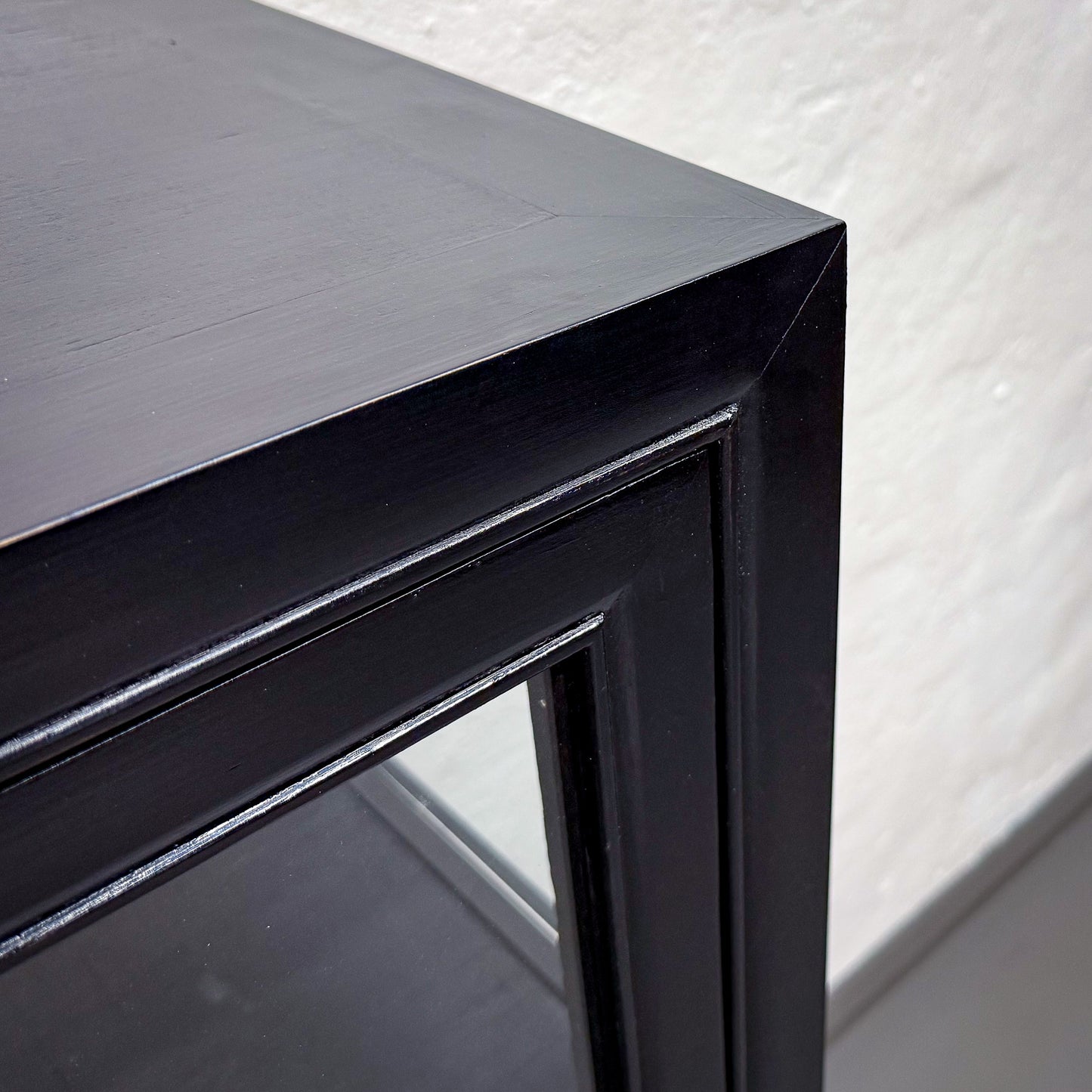 Black metal frame corner of a table with a white textured background