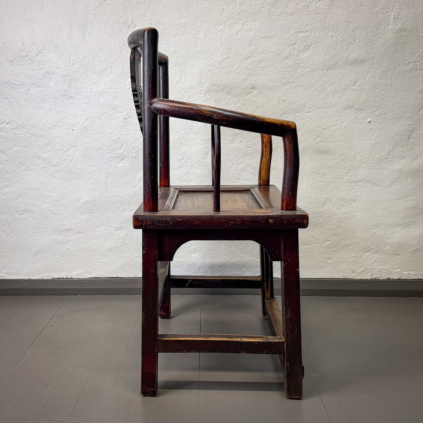 Vintage wooden chair against a textured white wall.