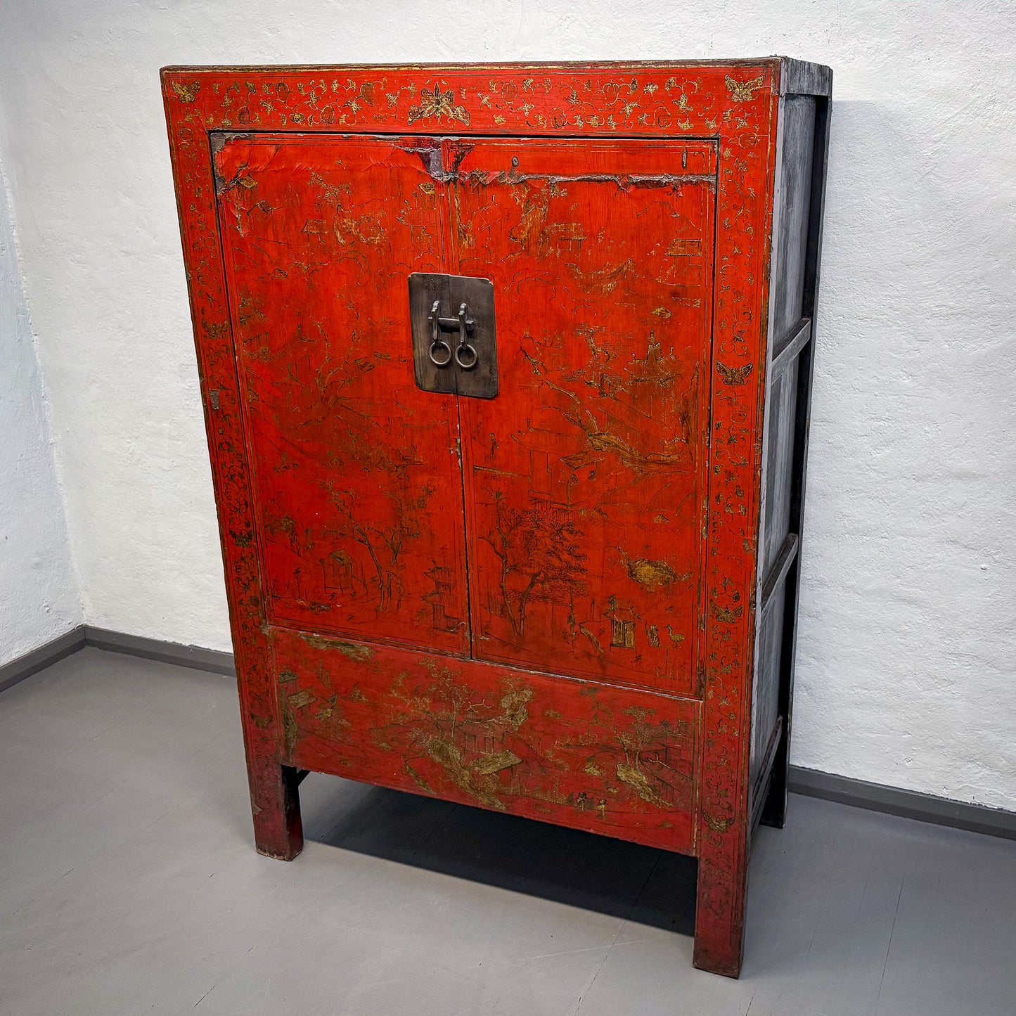 Red vintage cabinet with gold accents against a white wall