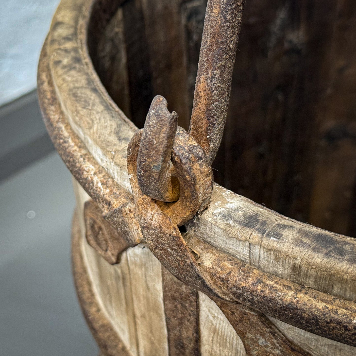 Close-up of a rusty metal hook on a wooden wheel with a blurred background