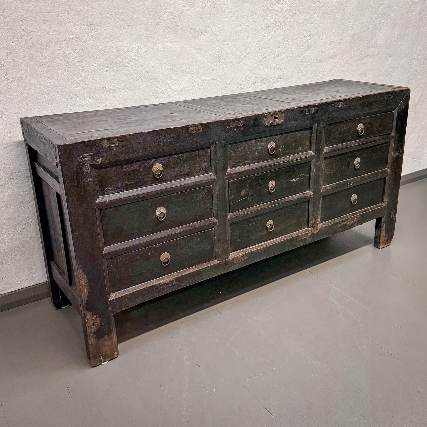 Vintage-style wooden dresser with multiple drawers against a plain wall.
