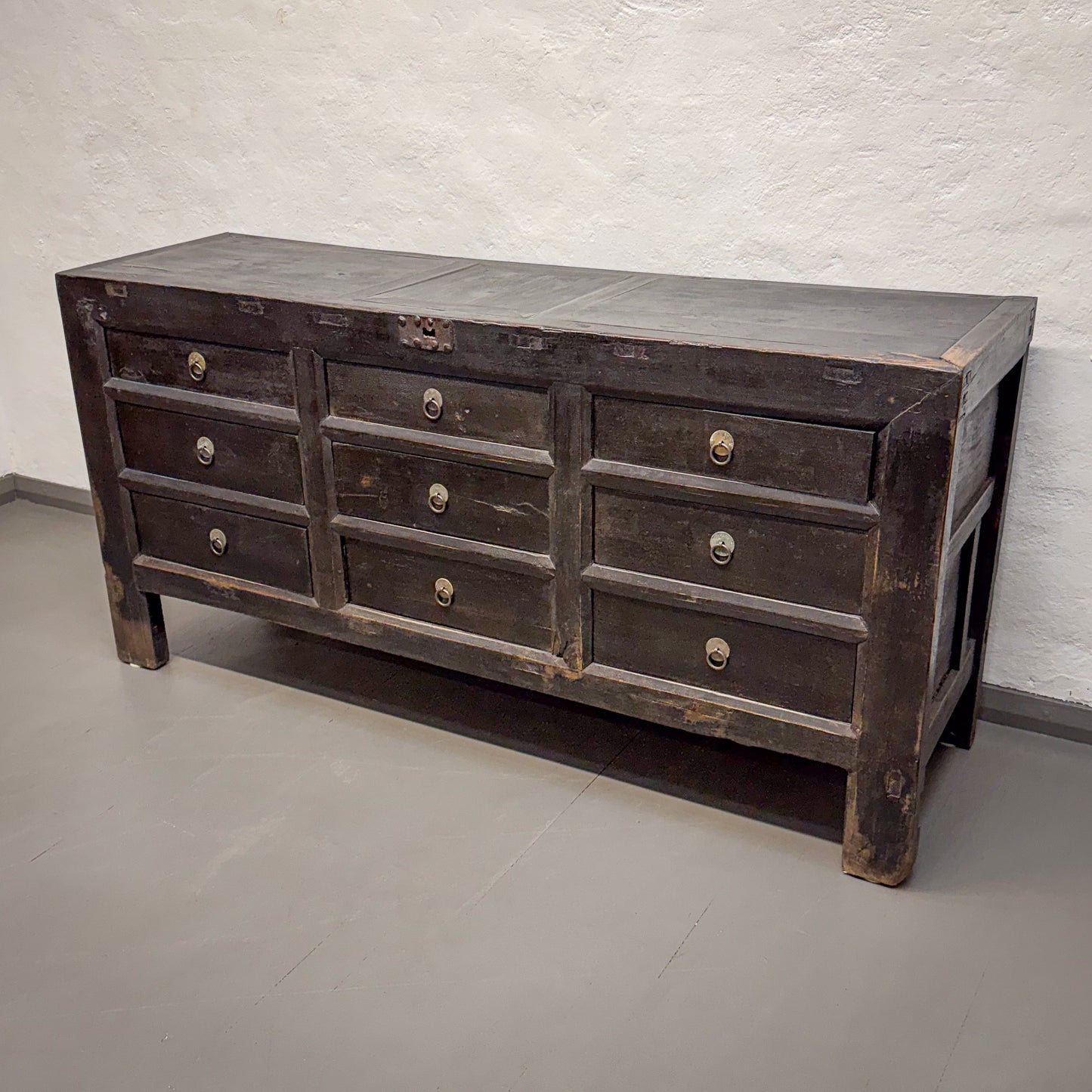 Vintage-style wooden dresser with multiple drawers against a plain wall.